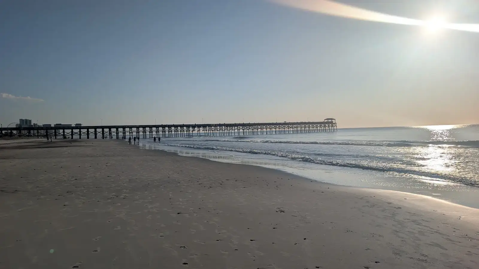 A long fishing pier at first light, the sun low over the water
